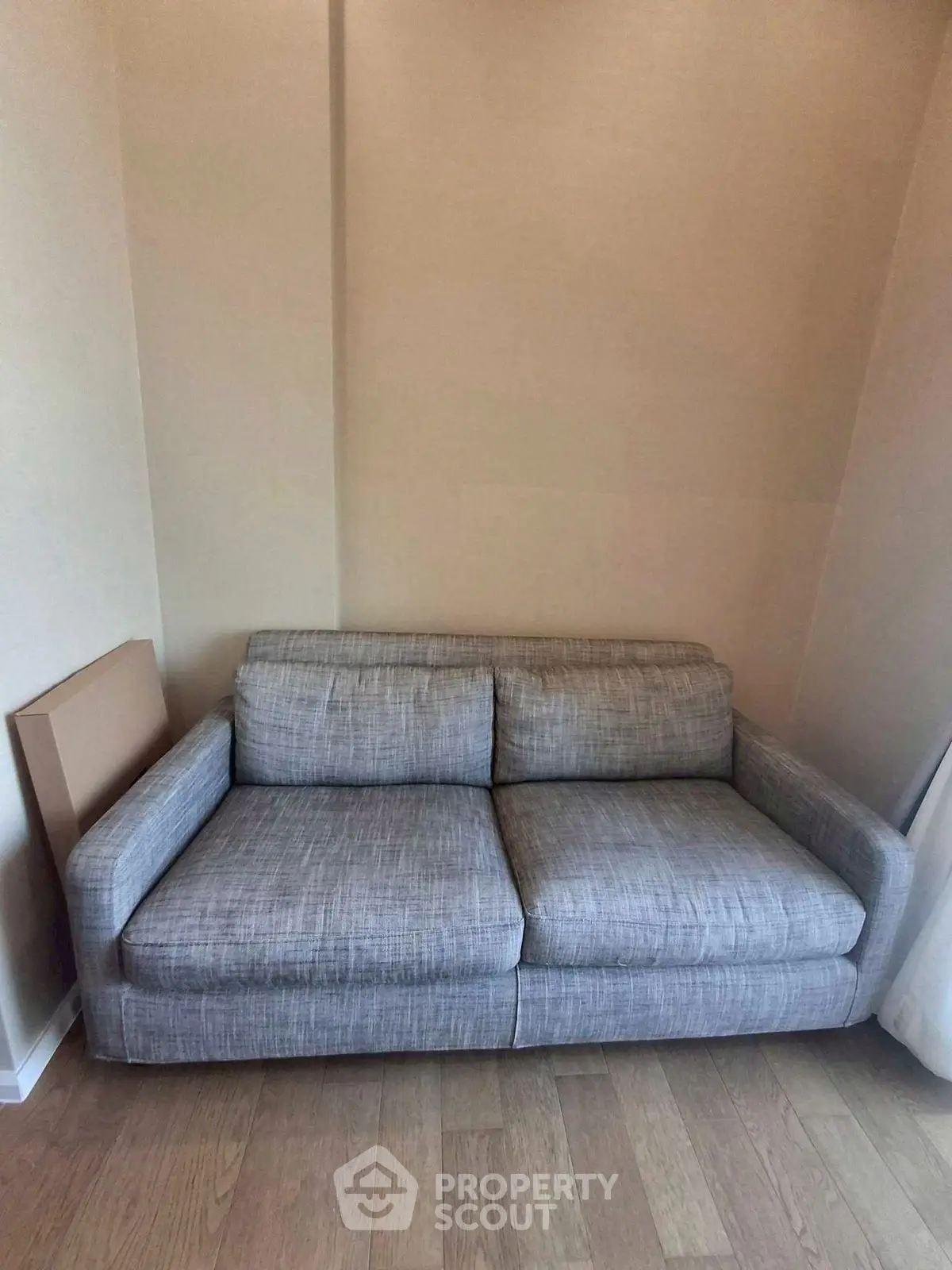 Cozy gray sofa in a minimalist living room with wooden flooring.