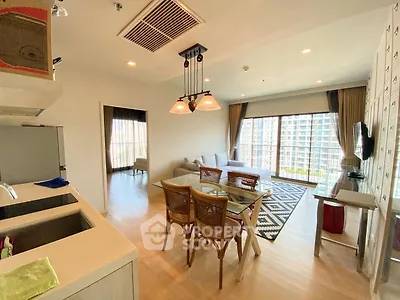 Spacious open-plan living room with modern kitchen and large windows offering city views.