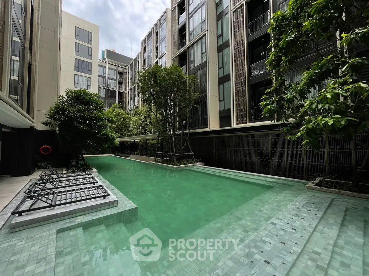 Luxurious condominium with a serene pool surrounded by lush greenery and modern architecture.