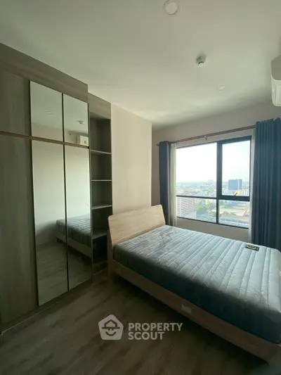 Spacious bedroom with large window offering stunning city views and modern furnishings.