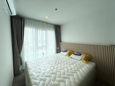 Modern bedroom with large window and stylish decor in a contemporary apartment.