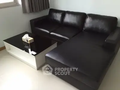 Modern living room with sleek black leather sofa and stylish coffee table.