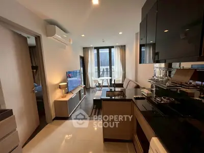 Modern open-layout living room with sleek kitchen and dining area, featuring contemporary furniture and natural light.
