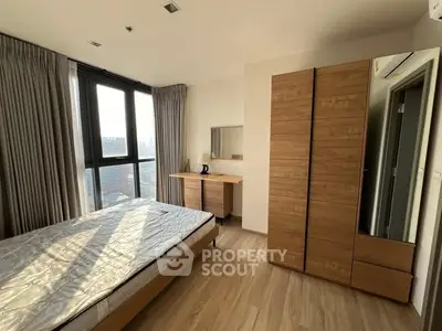 Modern bedroom with wooden furniture and large windows offering city views.