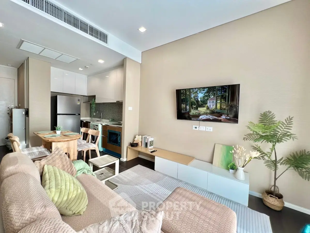 Modern living room with cozy sofa, wall-mounted TV, and stylish kitchen in open layout apartment.