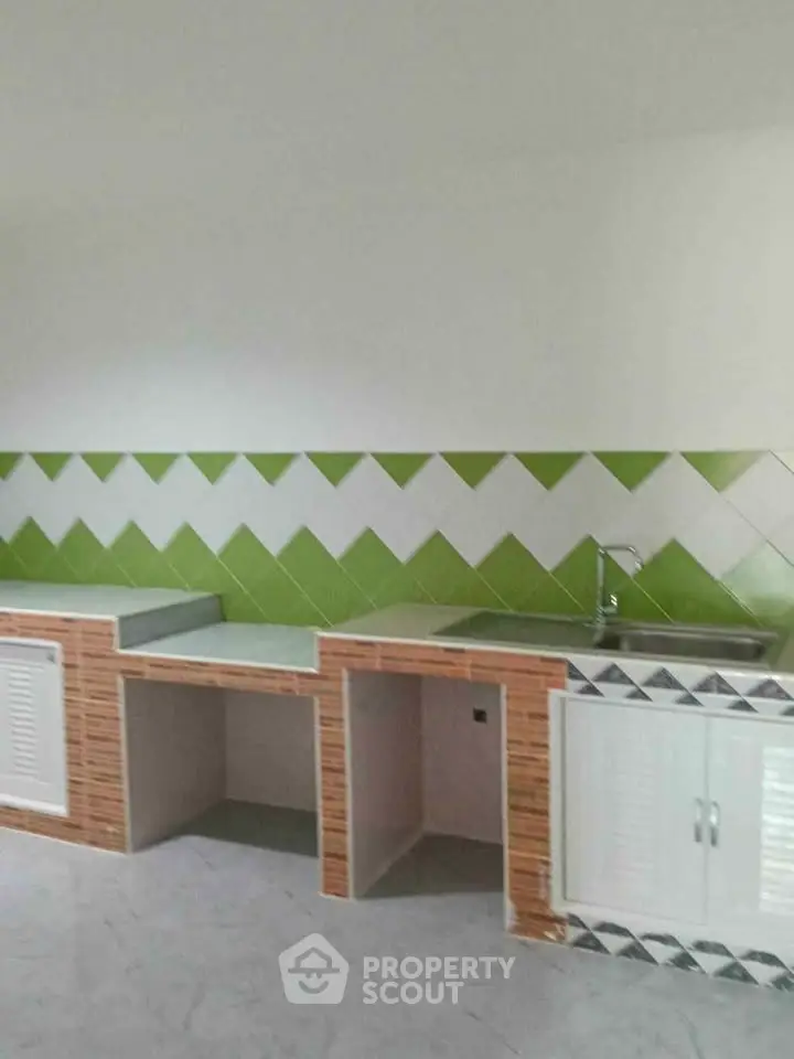 Modern kitchen with green and white tile backsplash and sleek countertops.