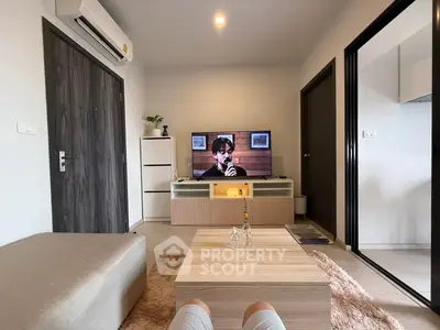 Modern living room with stylish decor and cozy ambiance, featuring a TV and air conditioning.