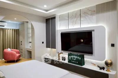 Luxurious modern bedroom with large TV and elegant decor, featuring a cozy reading nook.