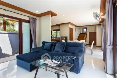 Spacious modern living room with elegant blue sofa and open dining area, perfect for family gatherings.