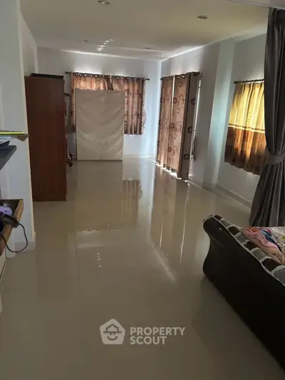 Spacious living room with glossy tiled floors and elegant curtains
