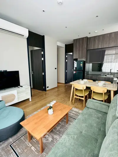 Modern living room with open kitchen, featuring stylish furniture and natural light.