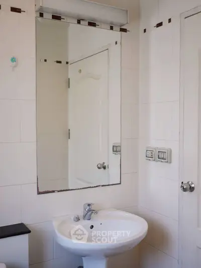 Modern bathroom with sleek sink and large mirror in a minimalist design.