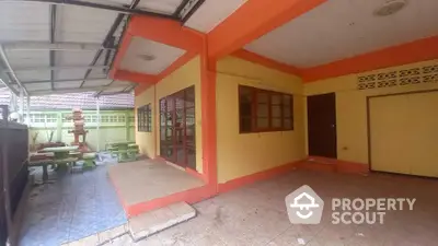 Spacious covered patio area with tiled flooring and vibrant orange accents