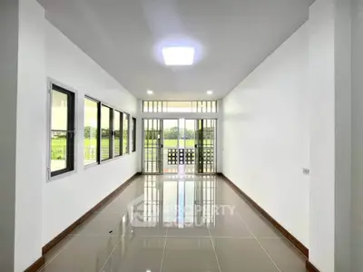 Spacious and bright living room with large windows and glossy tiled floor, offering a serene view.