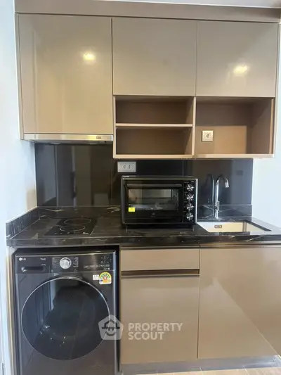 Modern compact kitchen with sleek cabinets, built-in oven, and washing machine