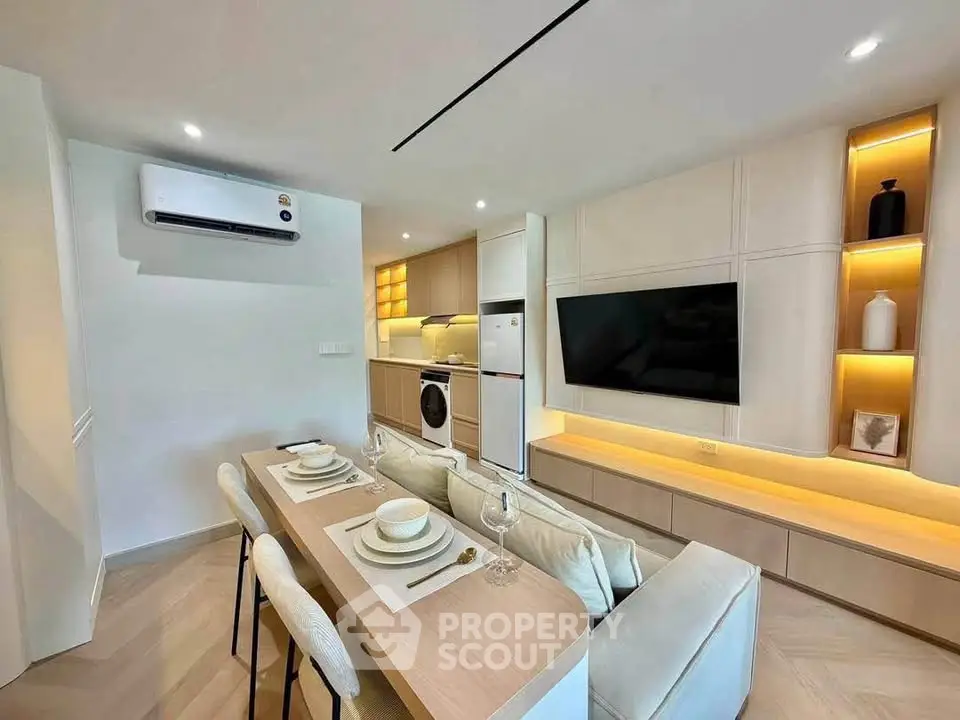 Modern open-plan living room with integrated kitchen and dining area, featuring sleek design and built-in appliances.