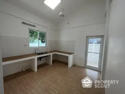 Spacious kitchen with modern white tiling, ample counter space, and natural light streaming through large windows, perfect for culinary enthusiasts.