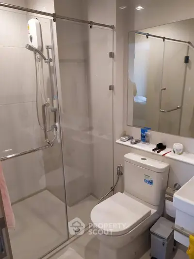 Modern bathroom with glass shower enclosure and sleek fixtures in a contemporary apartment.
