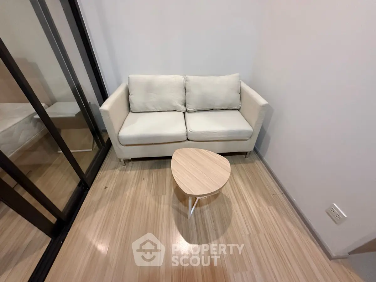 Cozy minimalist living room with modern sofa and sleek wooden flooring.