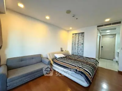 Spacious studio apartment with cozy bed and modern sofa, perfect for urban living.