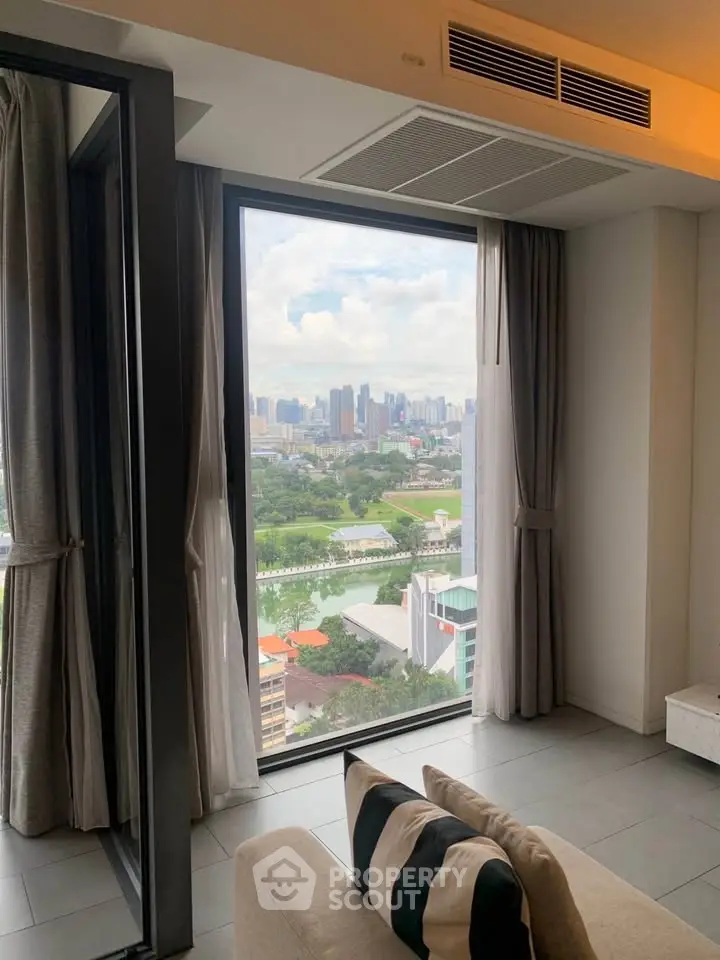 Stunning city view from modern living room with large window and cozy seating.