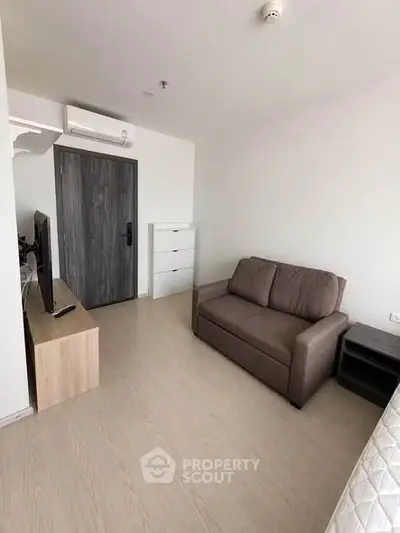 Modern living room with sleek furniture and minimalist design, featuring a cozy sofa and flat-screen TV.
