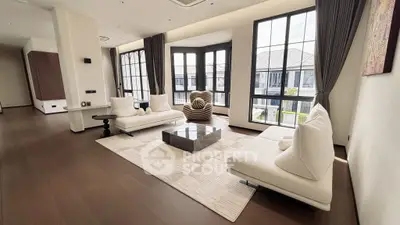 Spacious modern living room with large windows and elegant furnishings.