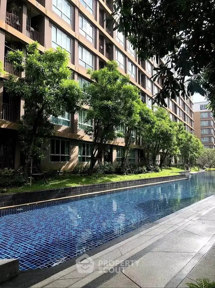 Modern apartment complex with lush greenery and inviting swimming pool.