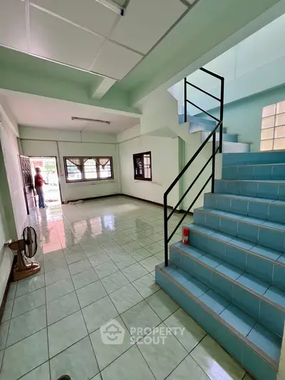 Spacious tiled interior with staircase and large windows, ideal for modern living.