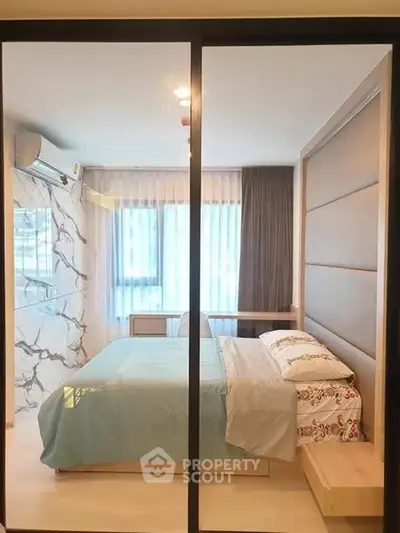 Modern bedroom with large window and stylish decor in a contemporary apartment.