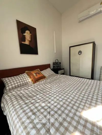 Cozy bedroom with checkered bedding and modern art, featuring air conditioning and ample natural light.