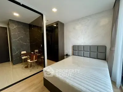 Modern bedroom with stylish decor and adjacent dining area in a contemporary apartment.