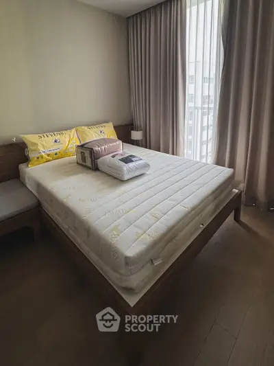 Cozy bedroom with modern decor and natural light through large window.