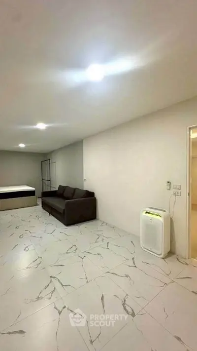 Spacious modern living room with marble flooring and minimalist furniture.