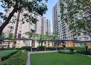 Modern residential complex with lush green garden and tall buildings.