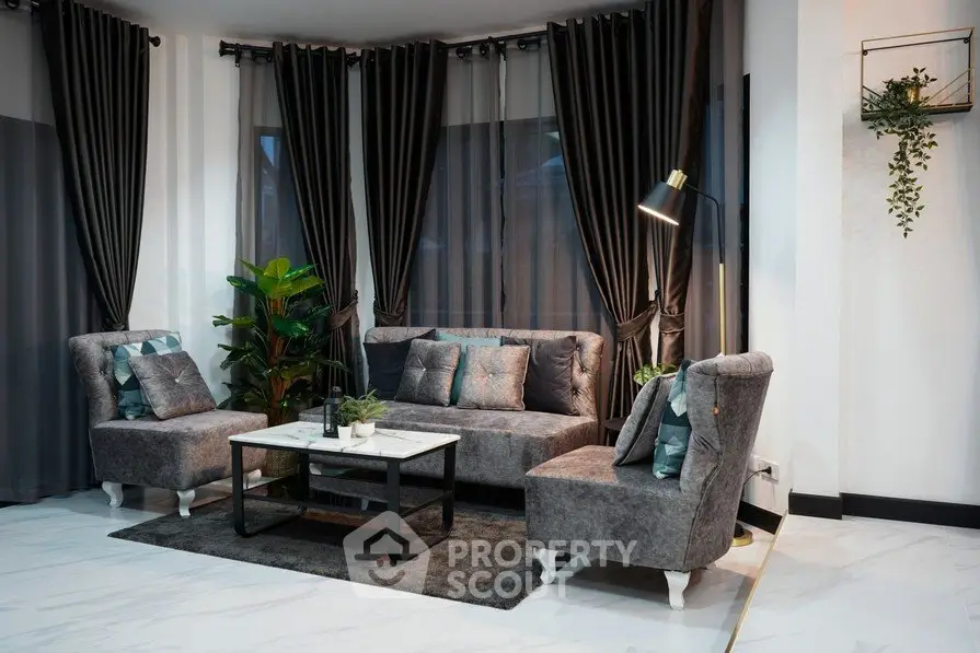 Elegant living room with plush gray seating, stylish coffee table, and lush green plants, exuding modern sophistication.