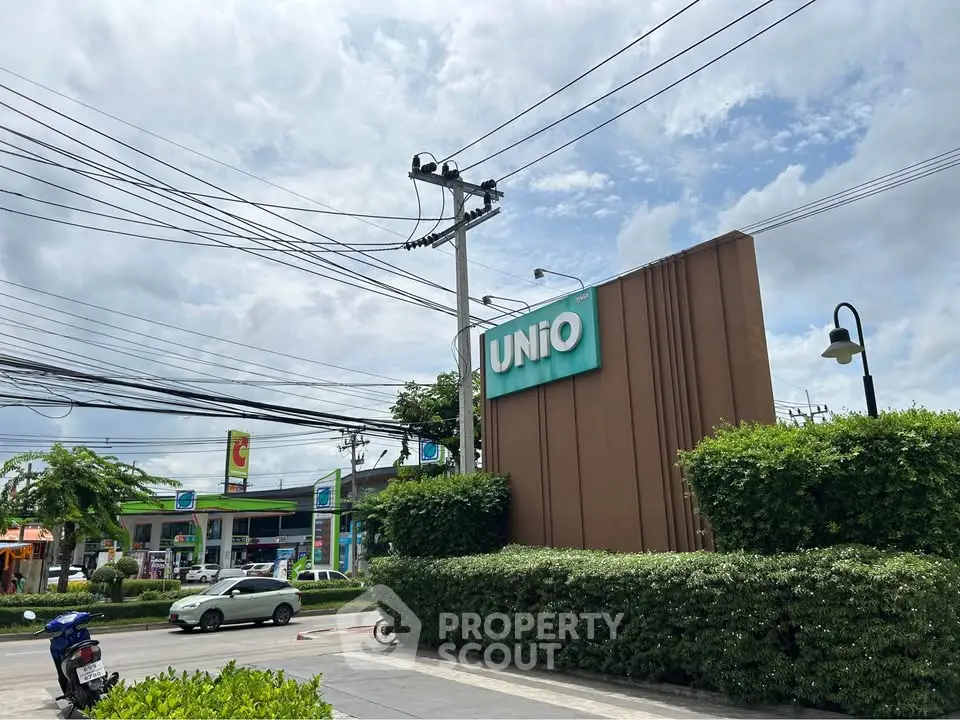 Modern residential complex entrance with lush greenery and clear sky