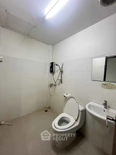 Minimalist bathroom with white tiles and modern fixtures, ideal for compact spaces.