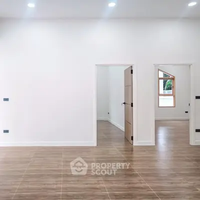 Spacious modern interior with wooden flooring and white walls, perfect for customization.
