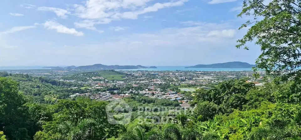 Stunning panoramic view of lush green landscape and distant ocean, perfect for serene living.