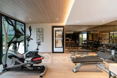 Modern gym with state-of-the-art equipment and mirrored walls in luxury residential building.