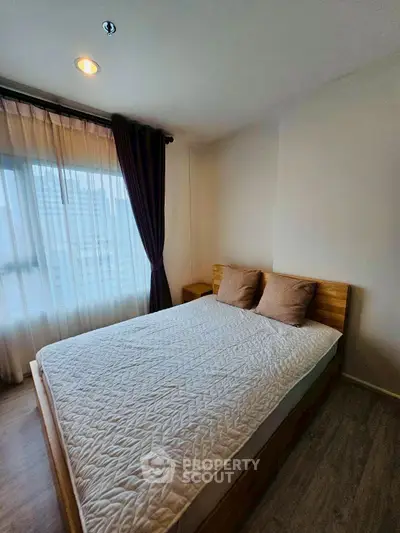 Cozy bedroom with large window and modern decor in urban apartment.