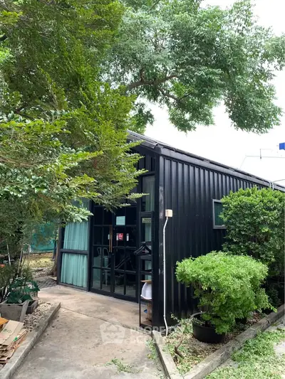 Charming black metal exterior house with lush greenery and inviting entrance.
