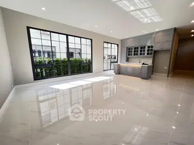 Spacious modern living room with large windows and sleek kitchen area