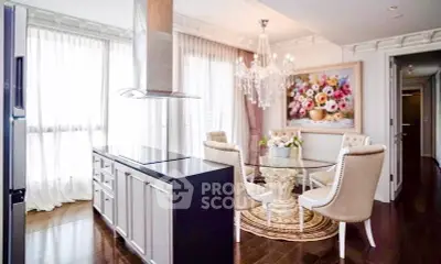 Luxurious dining area with elegant chandelier and floral artwork, featuring modern kitchen island.