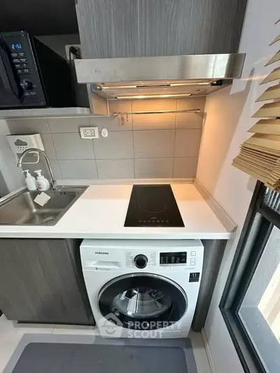 Modern compact kitchen with washing machine and electric stove in sleek apartment.