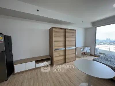 Modern studio apartment with city view, featuring sleek wooden furniture and bright natural lighting.