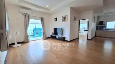 Spacious living room with wooden flooring and modern decor, featuring a large TV and sliding glass doors to a pool view.