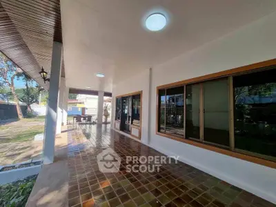 Spacious outdoor patio with tiled flooring and large windows, perfect for relaxation and entertainment.