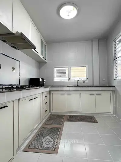 Modern kitchen with sleek cabinetry and gas stove in a bright, tiled space.